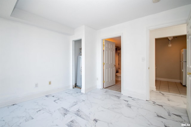 unfurnished bedroom featuring water heater, ensuite bathroom, and white fridge