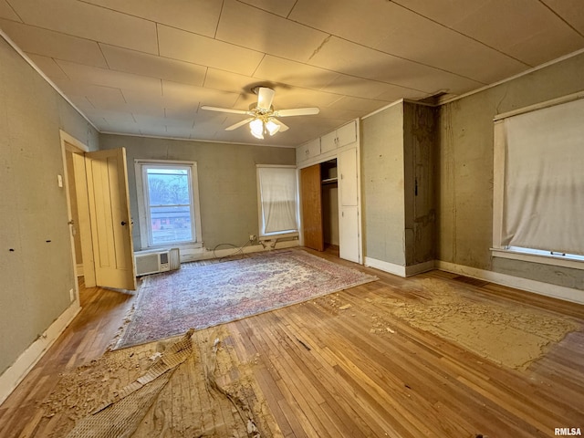 unfurnished bedroom with an AC wall unit and light wood-type flooring