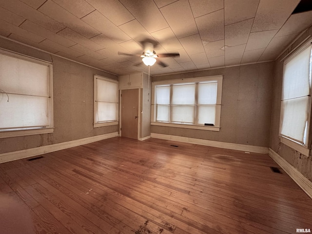 spare room with a wealth of natural light, hardwood / wood-style floors, and ceiling fan