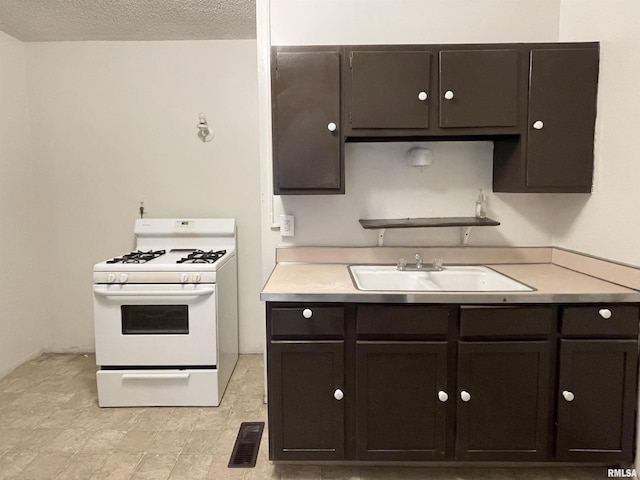 kitchen with white range with gas cooktop, sink, a textured ceiling, and dark brown cabinetry