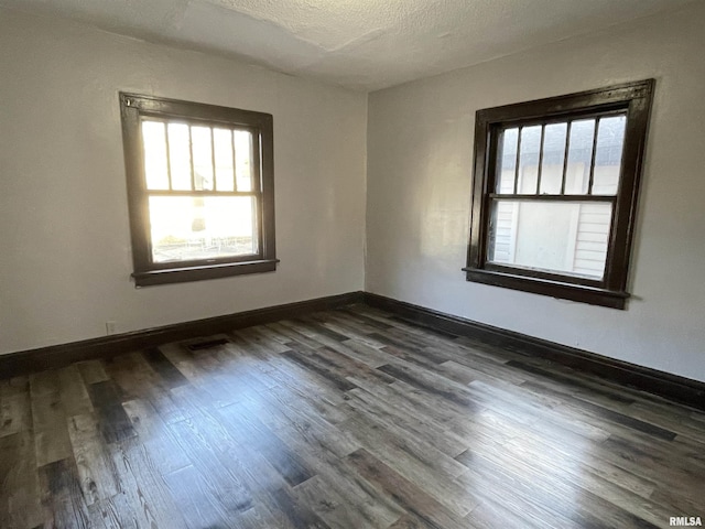 unfurnished room with dark hardwood / wood-style floors and a textured ceiling