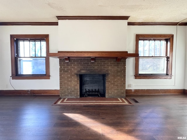 unfurnished living room featuring a brick fireplace, ornamental molding, dark hardwood / wood-style floors, and a textured ceiling