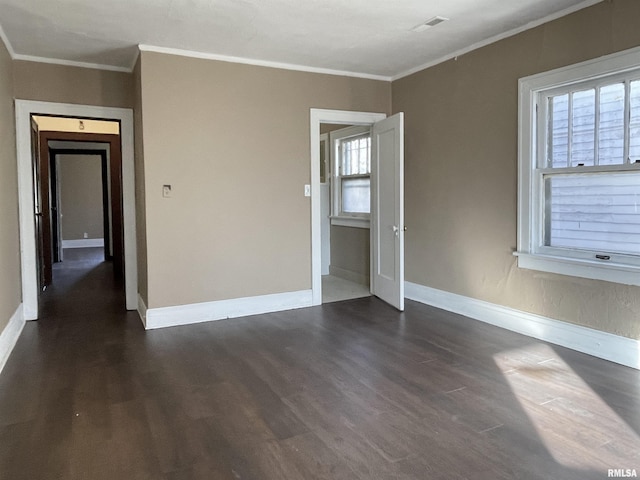 empty room with ornamental molding, plenty of natural light, and dark hardwood / wood-style floors