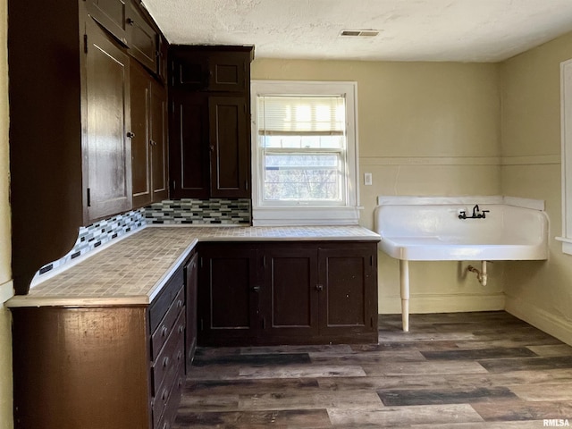 clothes washing area featuring a textured ceiling and dark hardwood / wood-style flooring