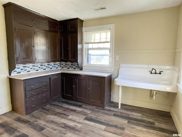 interior space with dark brown cabinetry, hardwood / wood-style floors, decorative backsplash, and a textured ceiling