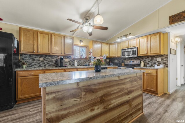 kitchen with stainless steel appliances, wood-type flooring, a kitchen island, and backsplash