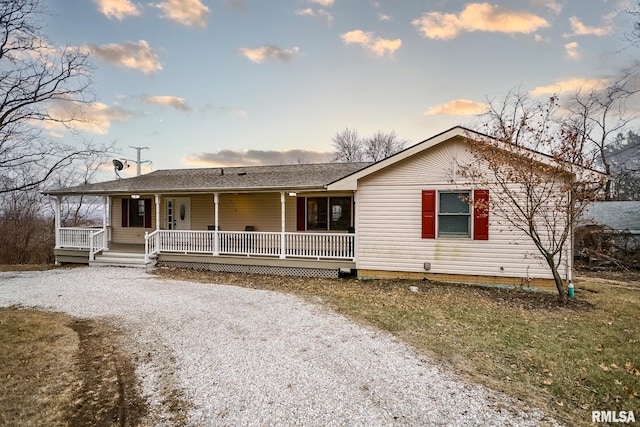 view of front of home with covered porch and gravel driveway