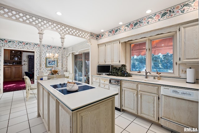 kitchen featuring dishwasher, sink, hanging light fixtures, black electric stovetop, and an inviting chandelier