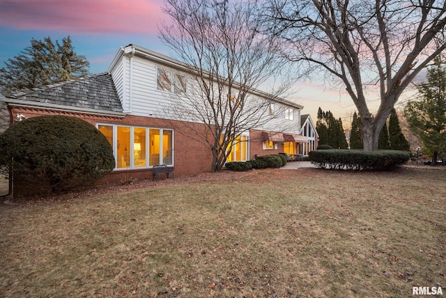 back house at dusk featuring a yard