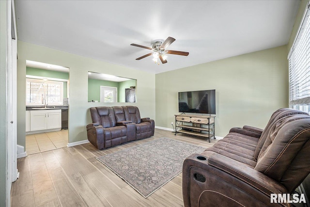 living room featuring ceiling fan, sink, and light wood-type flooring