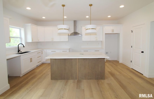 7023 N Water Oak Dr, Edwards, IL 61528 - kitchen featuring wall chimney exhaust hood, a sink, a kitchen island, light wood-style floors, and white cabinetry