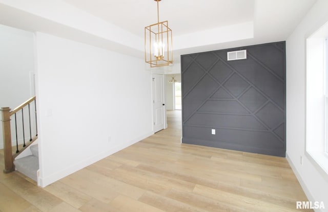 7023 N Water Oak Dr, Edwards, IL 61528 - unfurnished room featuring a raised ceiling, a decorative wall, light wood-style floors, a chandelier, and stairs