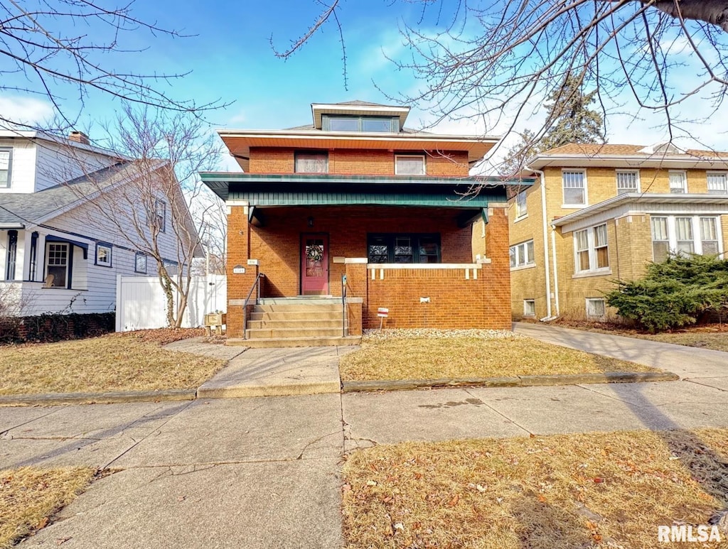 american foursquare style home with covered porch, brick siding, and fence