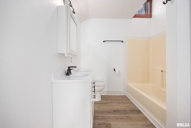 full bathroom featuring lofted ceiling, hardwood / wood-style flooring, vanity, toilet, and bathing tub / shower combination