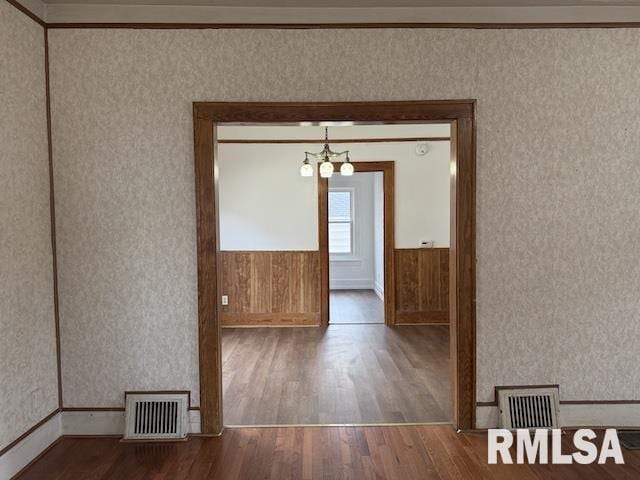 spare room with hardwood / wood-style floors and a chandelier