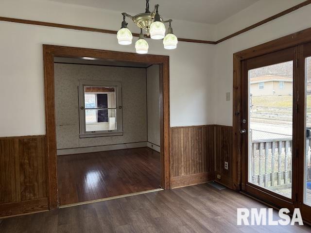 entryway featuring a notable chandelier, dark hardwood / wood-style floors, and wood walls