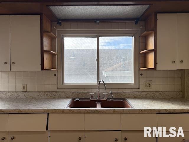 kitchen with tasteful backsplash, white cabinetry, sink, and a wealth of natural light