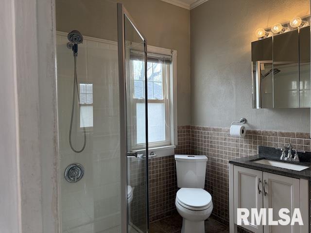 bathroom featuring crown molding, tile walls, vanity, a shower, and toilet