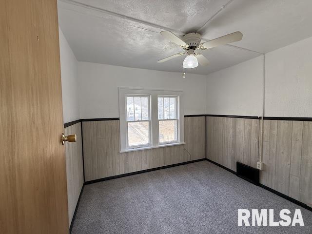 empty room featuring ceiling fan and wood walls