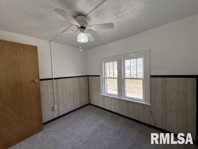 empty room with ceiling fan and wood walls