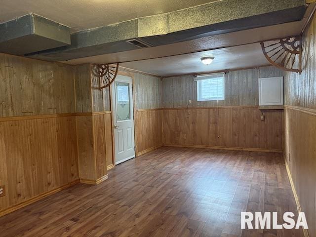 basement featuring dark hardwood / wood-style floors and wood walls