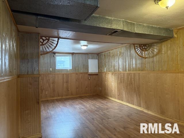 basement with hardwood / wood-style flooring and wood walls