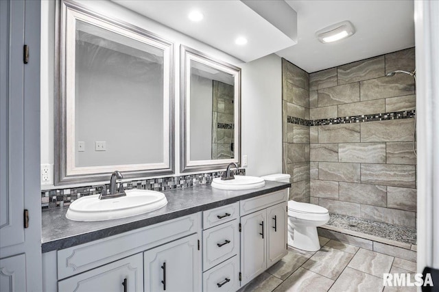 bathroom with vanity, tiled shower, backsplash, and toilet