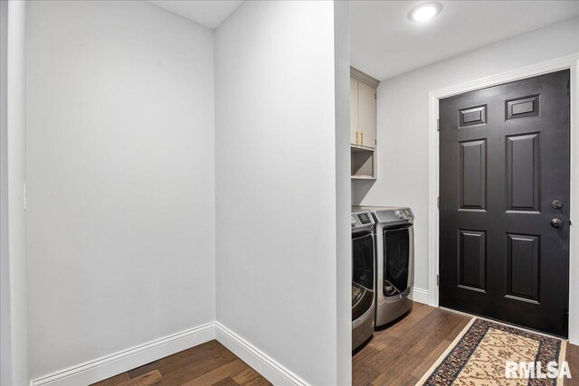 laundry area with cabinets, dark hardwood / wood-style floors, and washing machine and clothes dryer