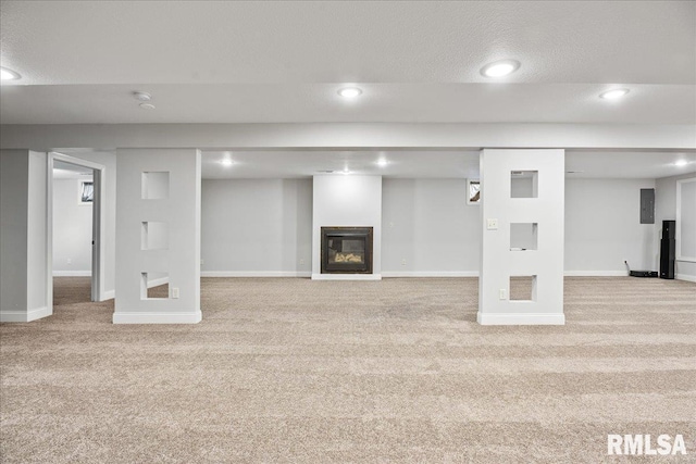 finished basement with a glass covered fireplace, carpet flooring, and baseboards