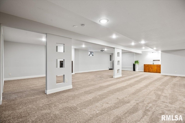 finished basement featuring a textured ceiling, baseboards, carpet flooring, and recessed lighting