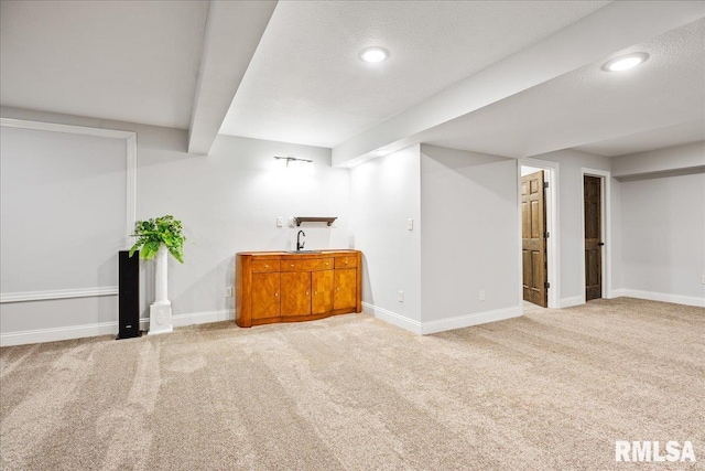 basement with sink, light carpet, and a textured ceiling