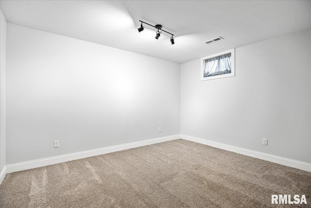 carpeted spare room with track lighting and a textured ceiling