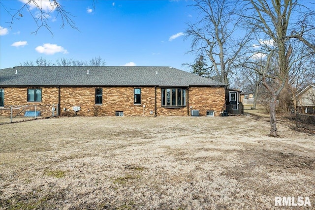 rear view of property featuring roof with shingles, central AC unit, and brick siding