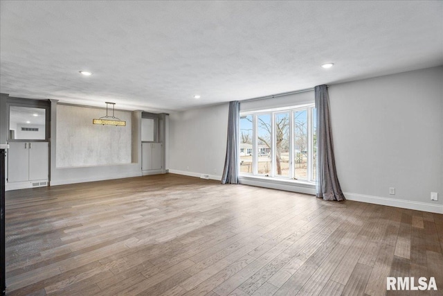 unfurnished living room featuring recessed lighting, visible vents, baseboards, and wood finished floors