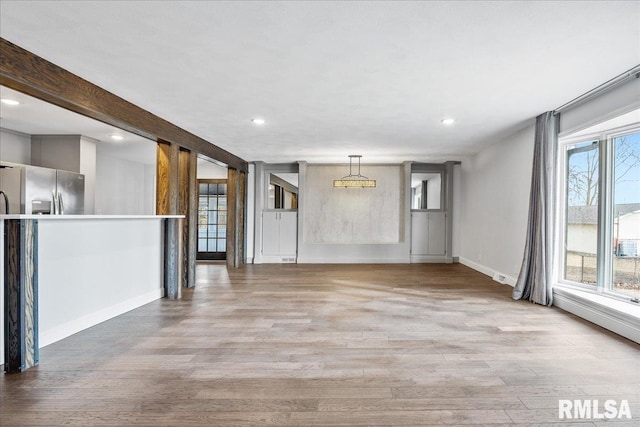 unfurnished living room featuring beam ceiling and light wood-type flooring