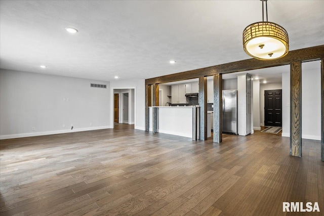 unfurnished living room with baseboards, visible vents, dark wood finished floors, and recessed lighting