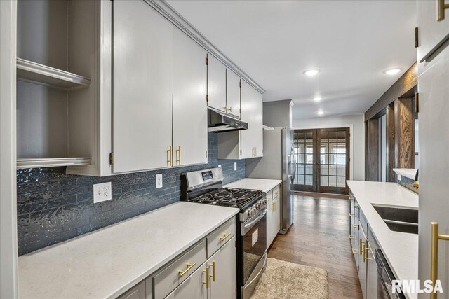 kitchen with sink, stainless steel gas stove, light hardwood / wood-style floors, decorative backsplash, and french doors