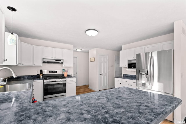 kitchen with sink, hanging light fixtures, stainless steel appliances, white cabinets, and kitchen peninsula