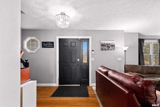 entrance foyer with wood-type flooring, a textured ceiling, and an inviting chandelier