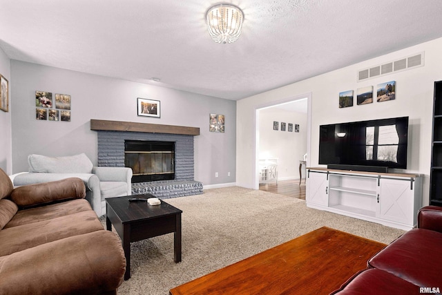 carpeted living room with a brick fireplace and a textured ceiling