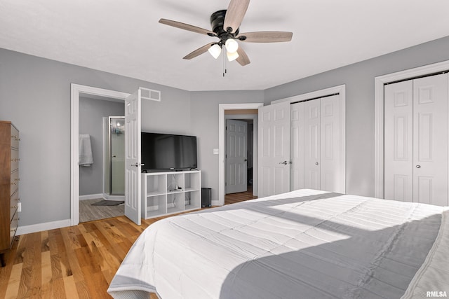 bedroom featuring ceiling fan, hardwood / wood-style flooring, multiple closets, and ensuite bathroom