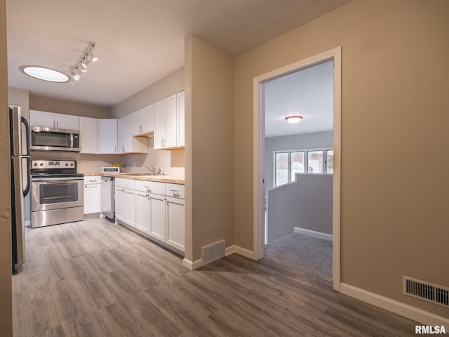 kitchen featuring white cabinetry, sink, hardwood / wood-style floors, and stainless steel appliances