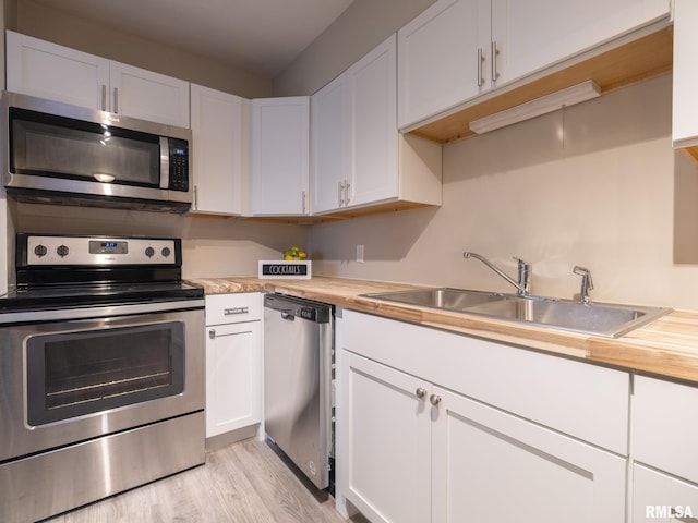 kitchen featuring wood counters, appliances with stainless steel finishes, white cabinetry, and sink