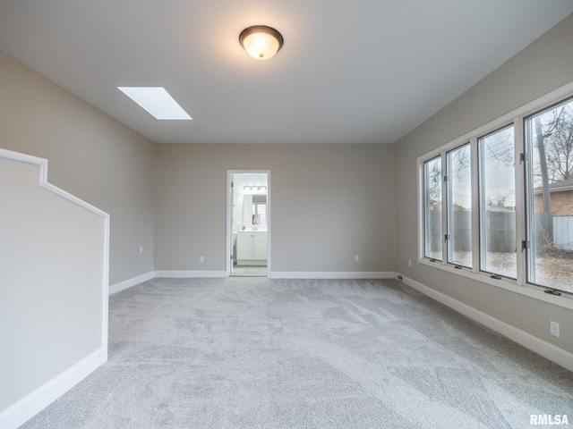 carpeted empty room featuring a skylight