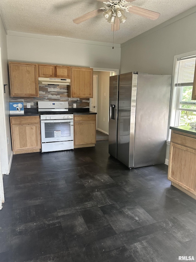 1822 N Sheridan Rd, Peoria, IL 61604 - kitchen with white gas stove, stainless steel fridge, under cabinet range hood, dark countertops, and a textured ceiling