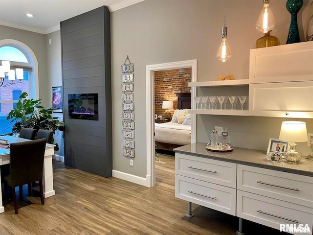 kitchen with ornamental molding, decorative light fixtures, white cabinets, and light hardwood / wood-style flooring