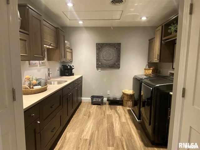 washroom with separate washer and dryer, sink, and light hardwood / wood-style flooring