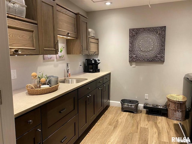 kitchen with dark brown cabinetry, sink, and light hardwood / wood-style flooring