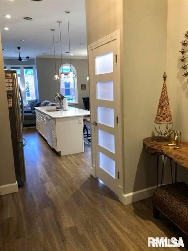 kitchen with sink, white cabinetry, stainless steel refrigerator, an island with sink, and pendant lighting