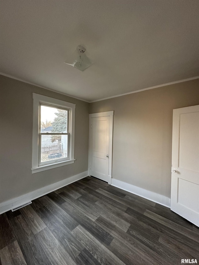 unfurnished room with ornamental molding and dark hardwood / wood-style flooring